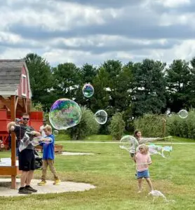 Children playing with giant bubbles outside.