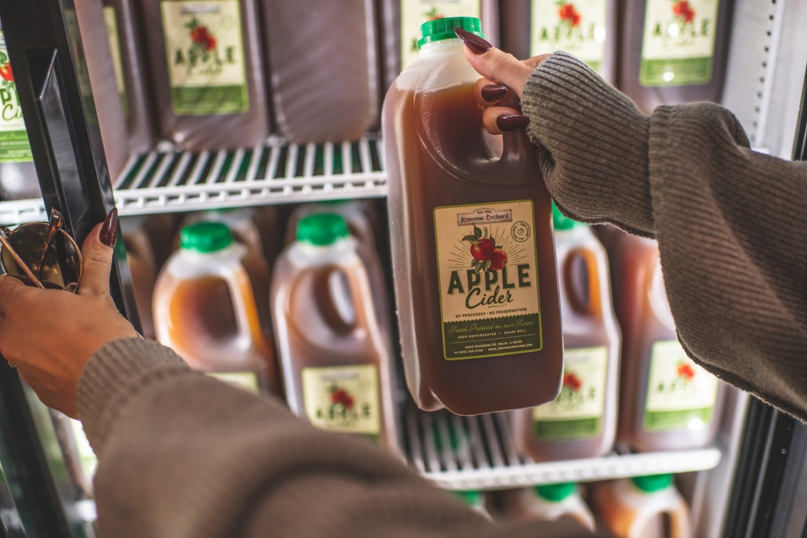 Person grabbing apple cider jug from fridge.