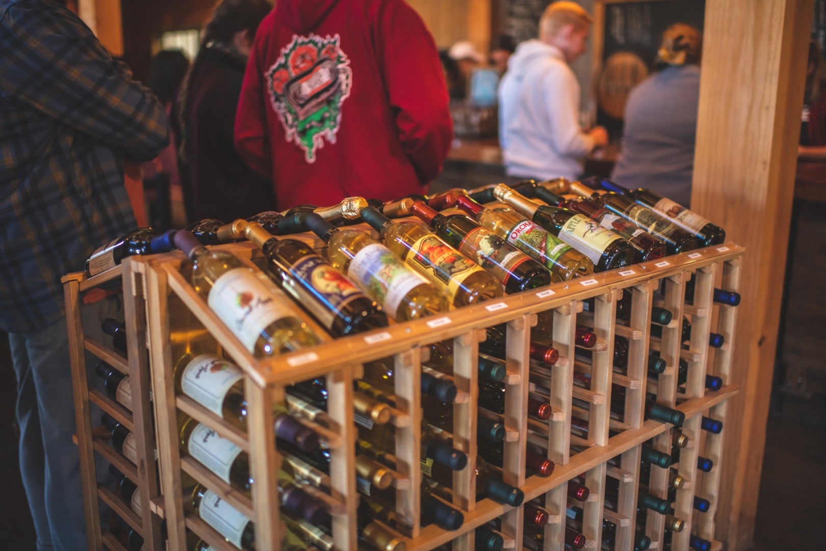 Wine bottles displayed on wooden rack in store.