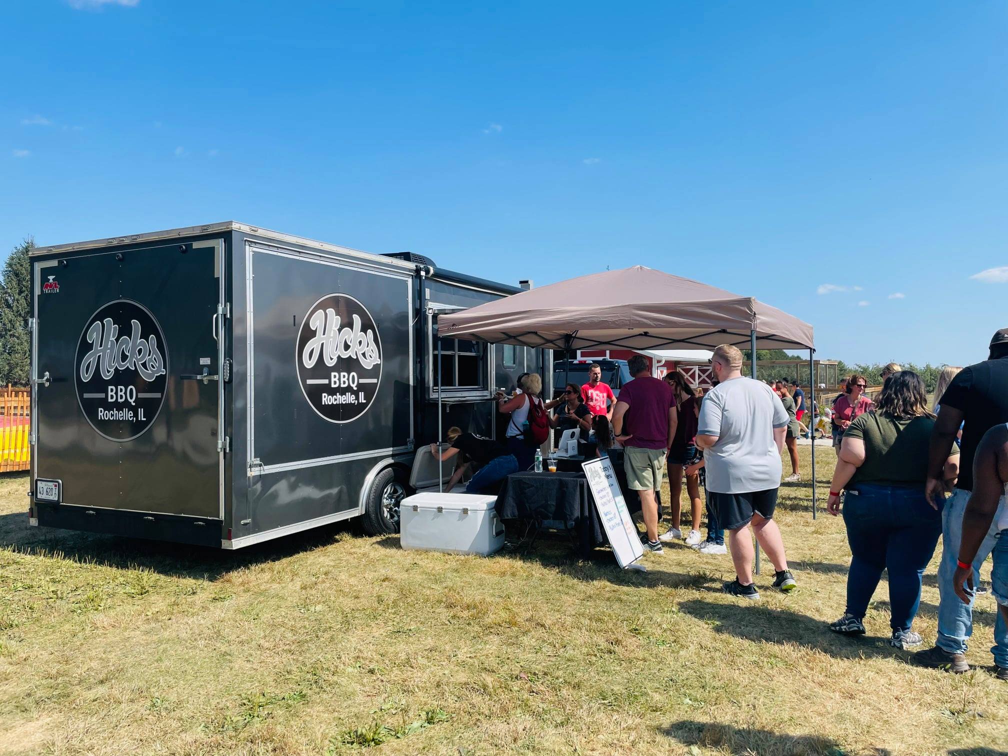 Food truck event with people enjoying barbecue.