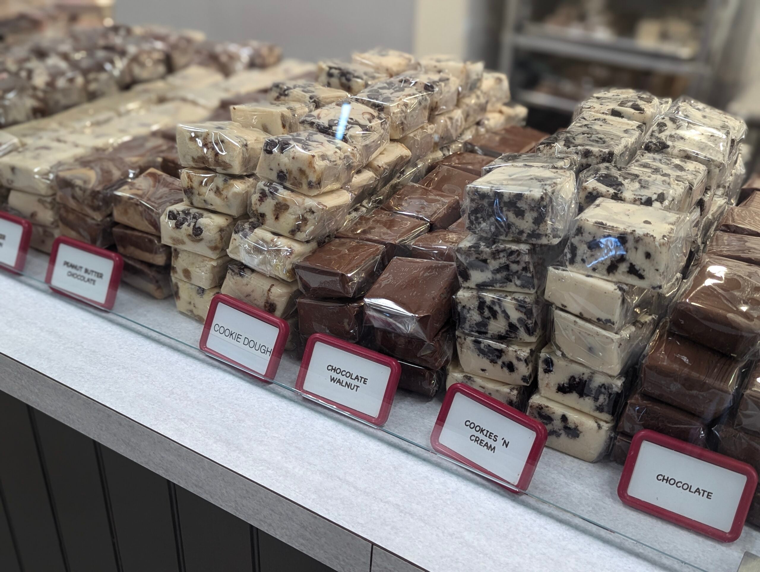Assorted fudge flavors displayed on store counter.