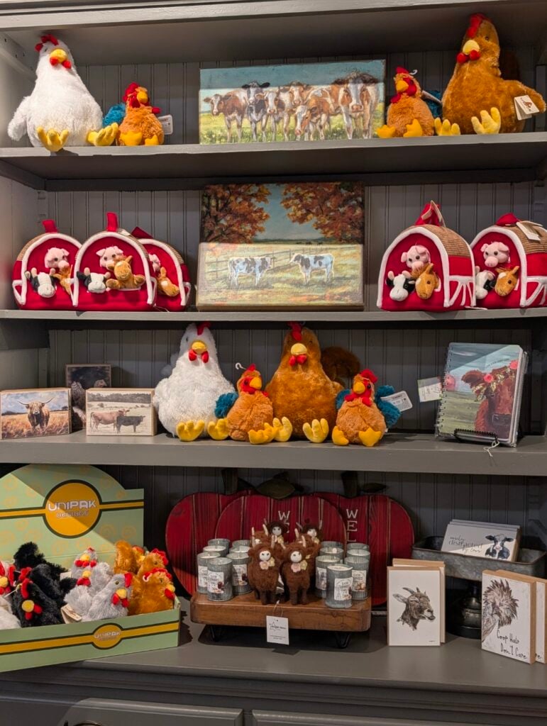 Plush farm animals and artwork on display shelves.