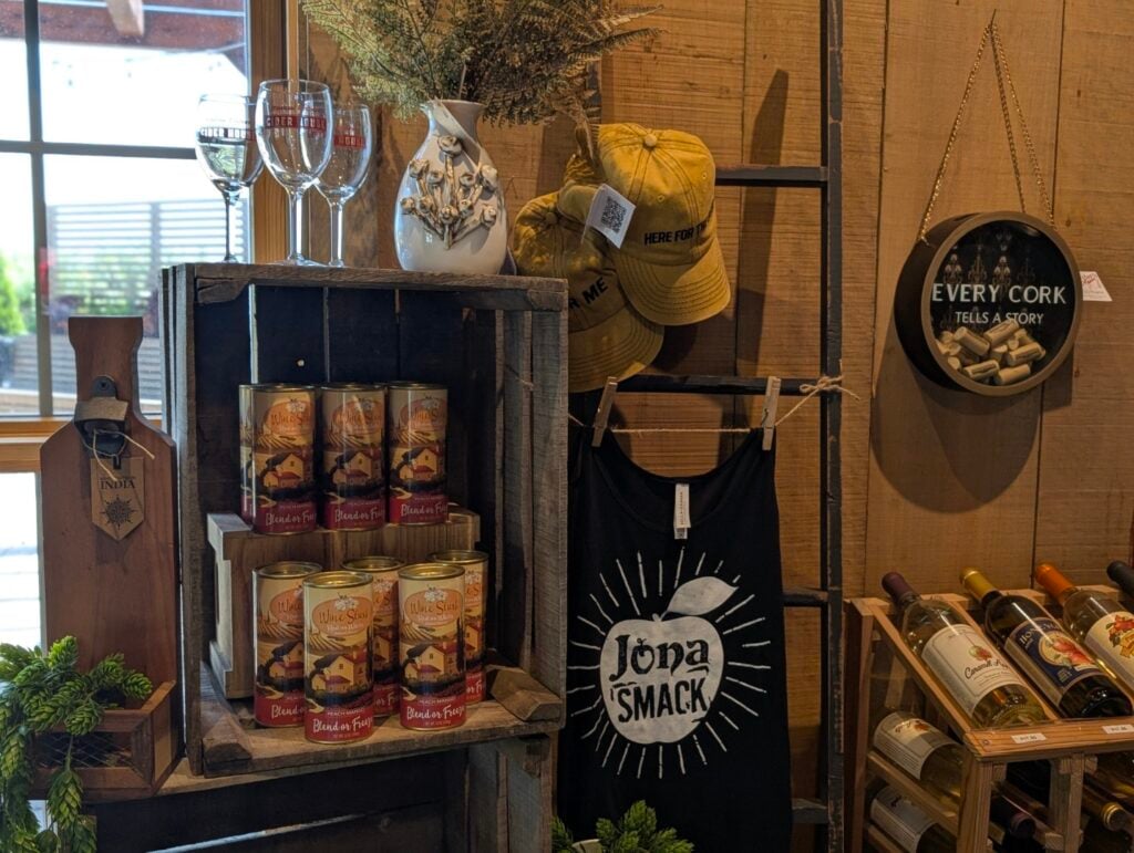 Rustic wine display with glasses, hats, and decor.