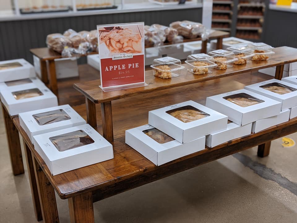 Display of packaged apple pies on wooden tables.